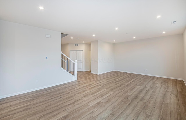 empty room with light wood-style floors, baseboards, stairway, and recessed lighting