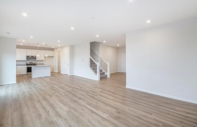 unfurnished living room with stairs, baseboards, light wood-style flooring, and recessed lighting