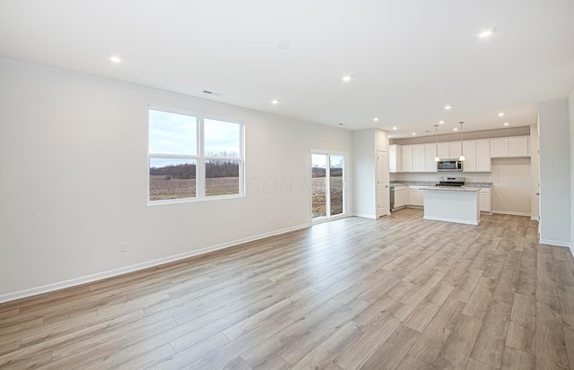 unfurnished living room with light wood-style floors, visible vents, baseboards, and recessed lighting