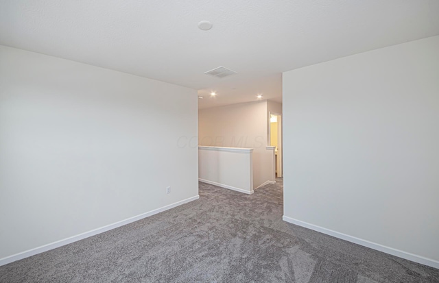 unfurnished room with carpet, visible vents, and baseboards