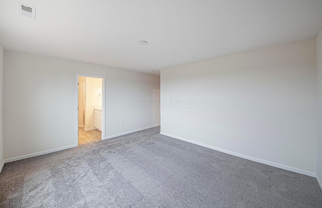 carpeted empty room featuring baseboards and visible vents