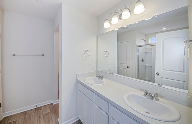 bathroom with a shower stall, baseboards, a sink, and wood finished floors