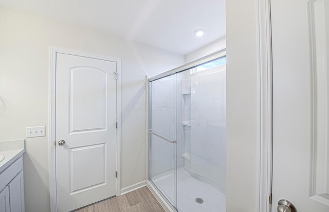 full bath with a stall shower, wood finished floors, and vanity