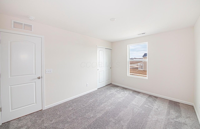 spare room with carpet floors, visible vents, and baseboards