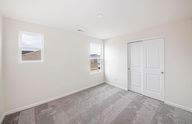 unfurnished bedroom with carpet, multiple windows, and baseboards