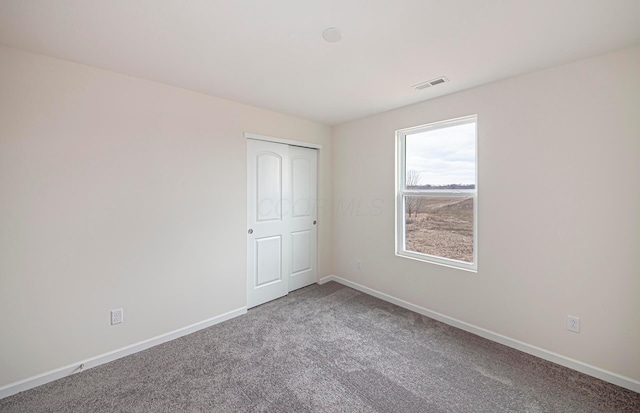 carpeted spare room with baseboards and visible vents