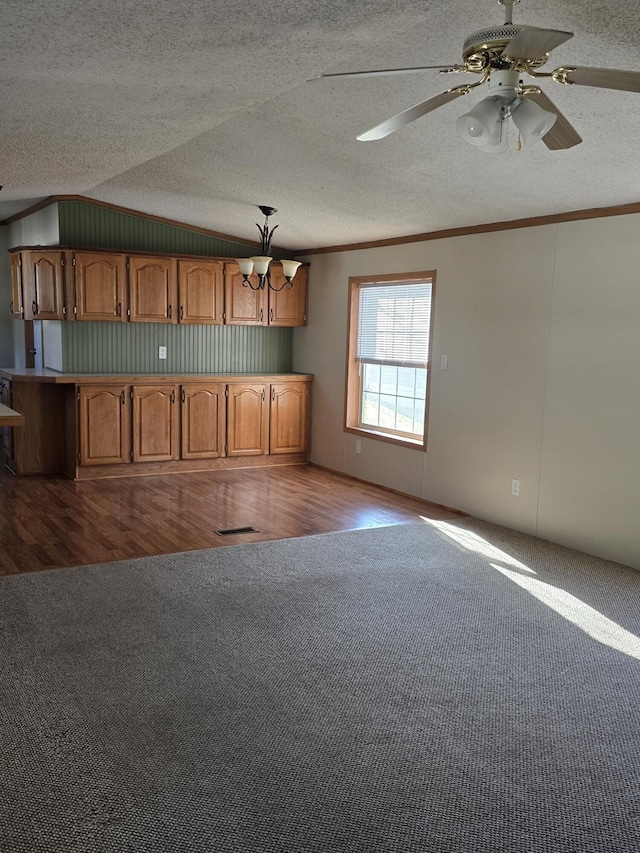 kitchen with a textured ceiling, light hardwood / wood-style floors, crown molding, and lofted ceiling