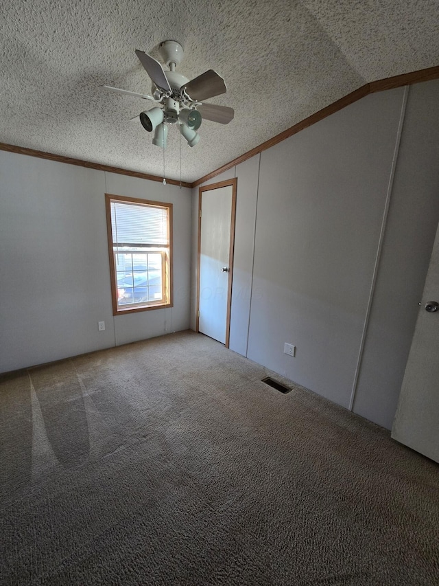 unfurnished bedroom featuring ornamental molding, a textured ceiling, vaulted ceiling, ceiling fan, and carpet floors