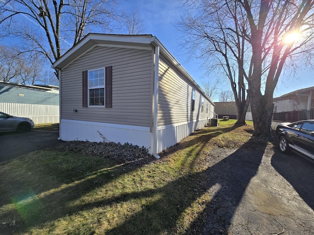 view of side of property featuring a lawn and central air condition unit