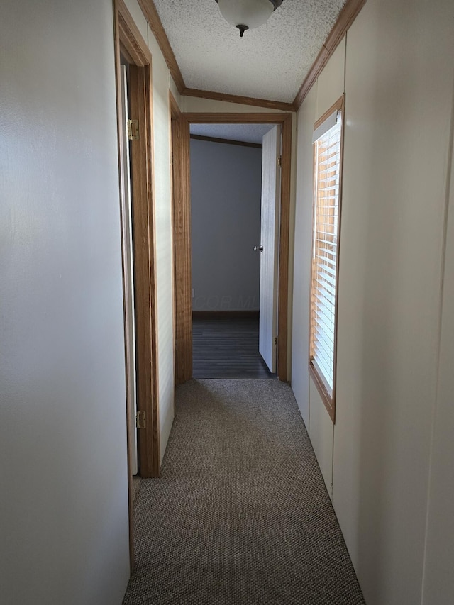 hallway featuring a textured ceiling, vaulted ceiling, dark carpet, and crown molding