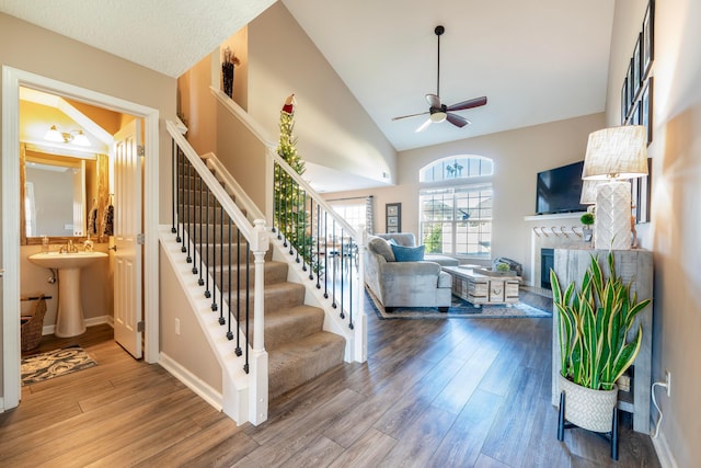 stairway featuring hardwood / wood-style flooring, ceiling fan, sink, and a fireplace