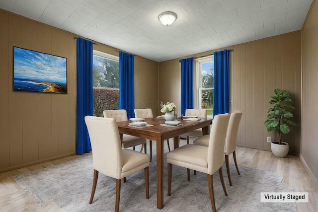 dining space featuring wood walls and light hardwood / wood-style floors