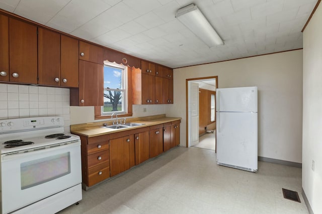 kitchen featuring white appliances, backsplash, and sink