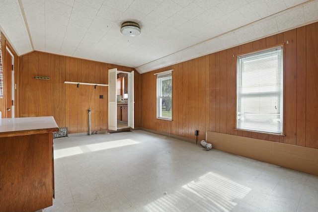 unfurnished room featuring vaulted ceiling and wooden walls