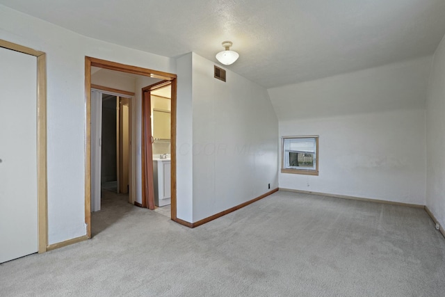 unfurnished room with light colored carpet and lofted ceiling