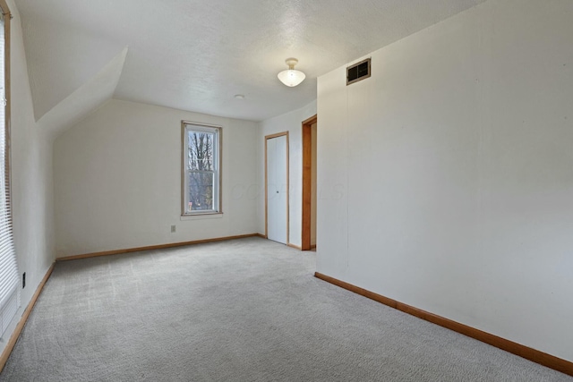 additional living space with light colored carpet and vaulted ceiling