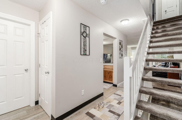 staircase featuring hardwood / wood-style floors and a textured ceiling