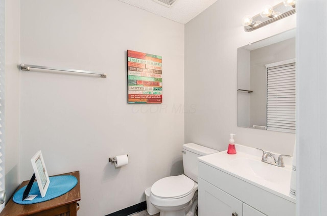 bathroom featuring a textured ceiling, vanity, and toilet