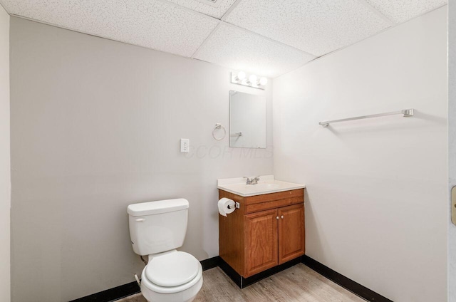 bathroom featuring a paneled ceiling, hardwood / wood-style floors, vanity, and toilet