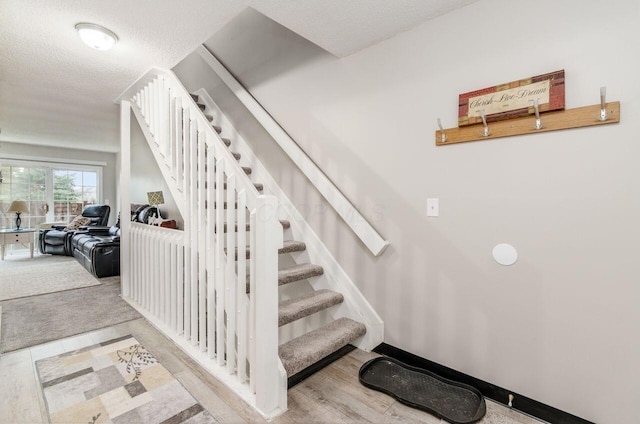 stairway with hardwood / wood-style floors and a textured ceiling