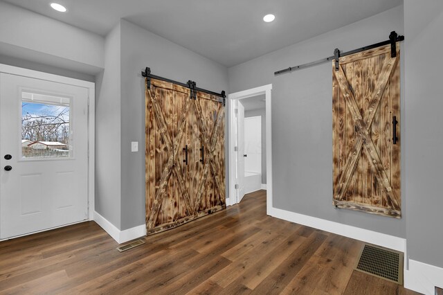 entryway with dark wood-type flooring and a barn door