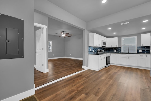 kitchen featuring stainless steel appliances, dark hardwood / wood-style flooring, electric panel, and white cabinets