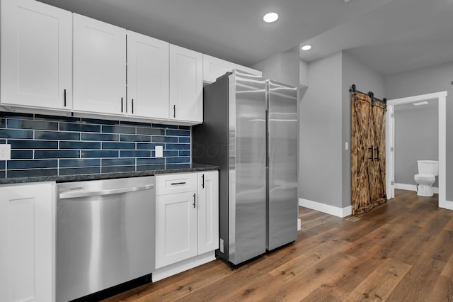 kitchen featuring tasteful backsplash, white cabinetry, stainless steel appliances, and a barn door