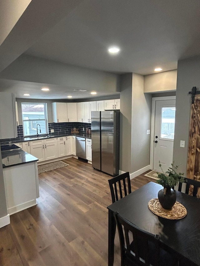 kitchen with sink, appliances with stainless steel finishes, white cabinetry, backsplash, and dark hardwood / wood-style floors