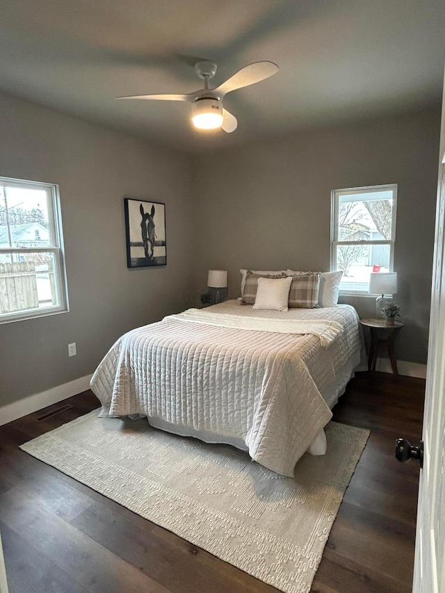 bedroom featuring multiple windows, dark wood-type flooring, and ceiling fan