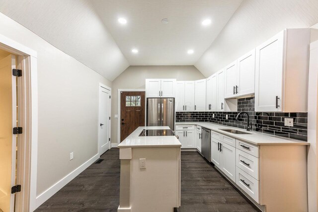 kitchen with a center island, white cabinets, sink, vaulted ceiling, and stainless steel appliances