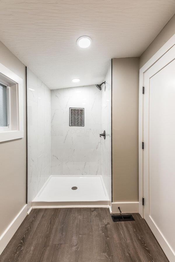 bathroom with wood-type flooring and tiled shower