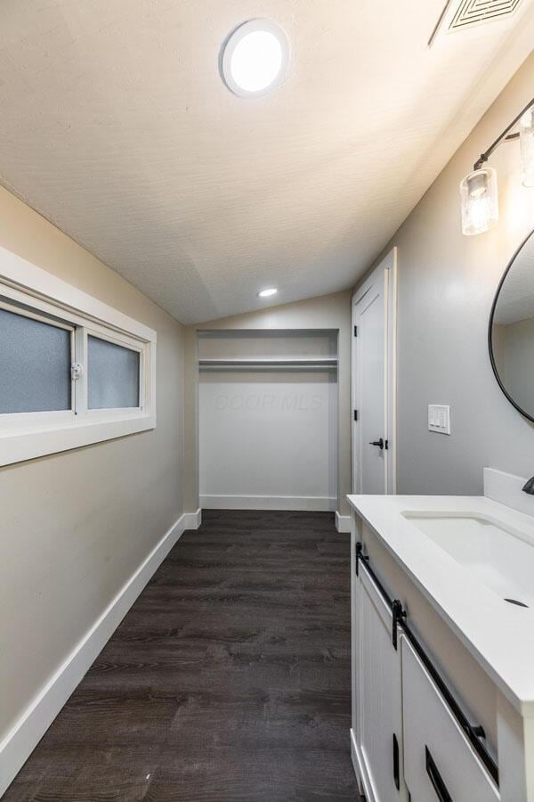 bathroom featuring hardwood / wood-style floors, vanity, and vaulted ceiling