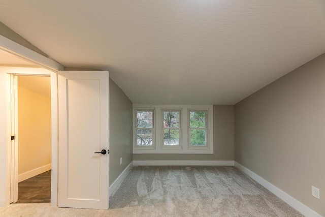 interior space featuring light colored carpet and vaulted ceiling