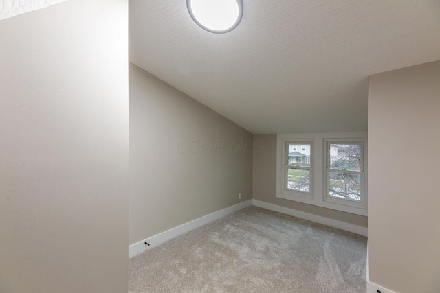 carpeted spare room with a textured ceiling and vaulted ceiling