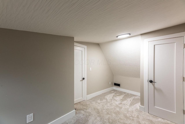 laundry room with light colored carpet and a textured ceiling