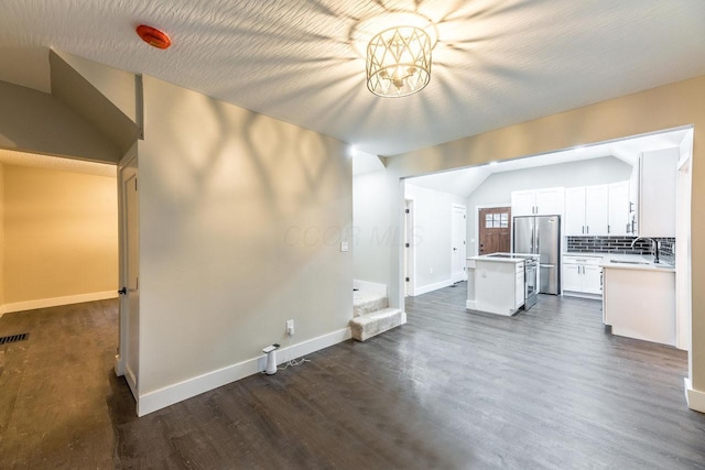 unfurnished living room featuring sink, vaulted ceiling, a textured ceiling, dark hardwood / wood-style flooring, and a chandelier