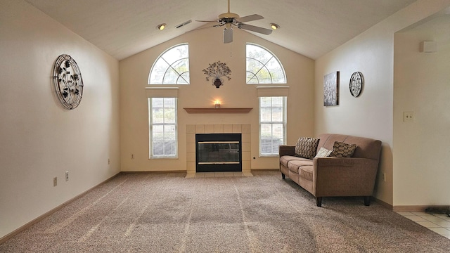 living room featuring high vaulted ceiling, ceiling fan, light carpet, and a tile fireplace