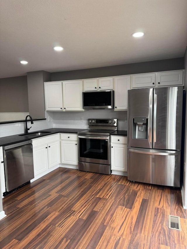 kitchen featuring white cabinets, sink, appliances with stainless steel finishes, and dark wood-type flooring