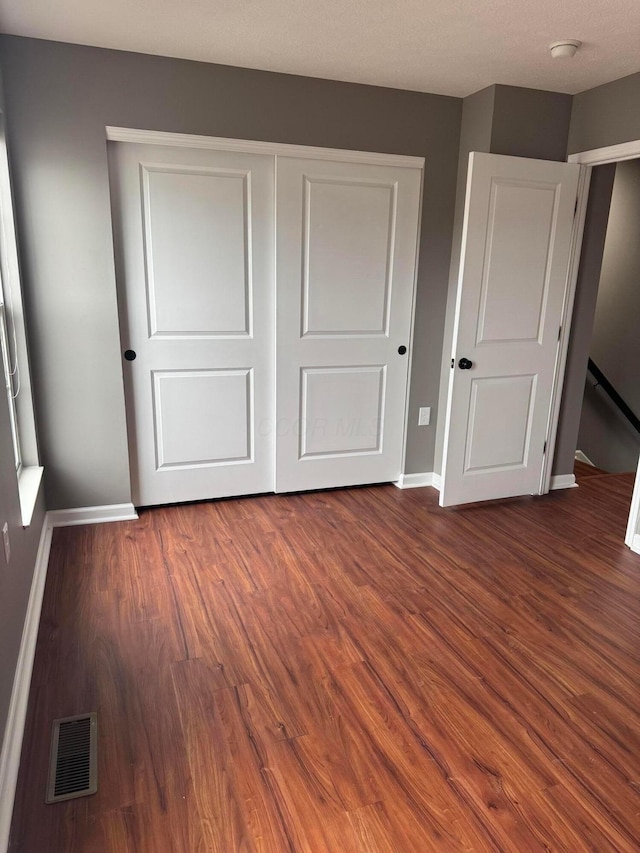 unfurnished bedroom with a closet and dark hardwood / wood-style floors