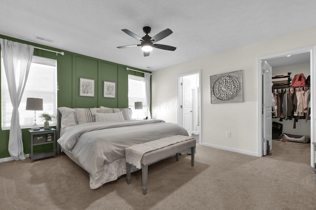 carpeted bedroom featuring a walk in closet, ceiling fan, a closet, and multiple windows