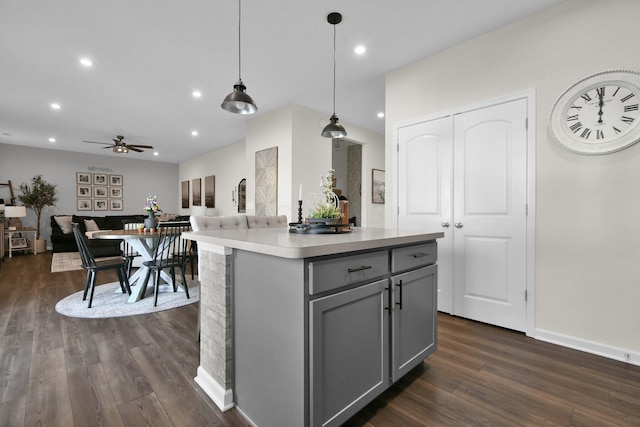 kitchen featuring ceiling fan, gray cabinets, dark hardwood / wood-style floors, a kitchen island, and hanging light fixtures