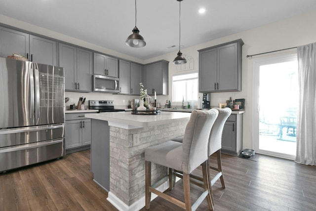 kitchen featuring stainless steel appliances, hanging light fixtures, and gray cabinetry