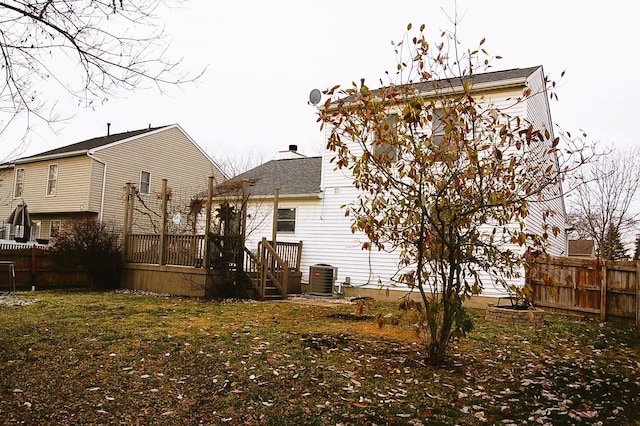 rear view of property featuring a lawn, a wooden deck, and central AC