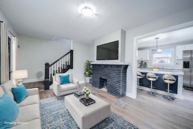 living room featuring a brick fireplace and light hardwood / wood-style floors