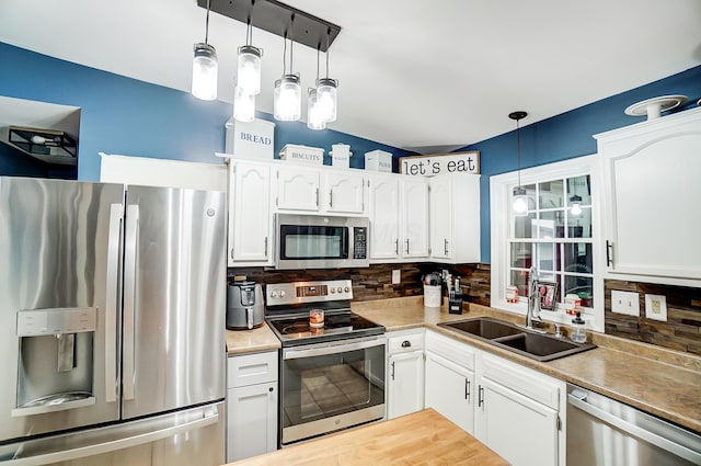 kitchen featuring white cabinets, appliances with stainless steel finishes, backsplash, and hanging light fixtures