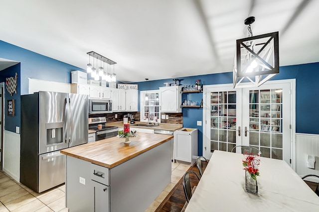 kitchen featuring white cabinets, sink, decorative light fixtures, a kitchen island, and stainless steel appliances