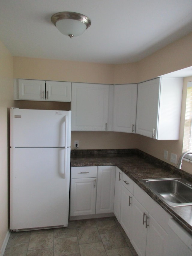 kitchen featuring dishwasher, white refrigerator, white cabinetry, and sink