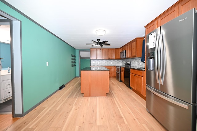 kitchen featuring ceiling fan, backsplash, stainless steel appliances, a kitchen island, and light wood-type flooring