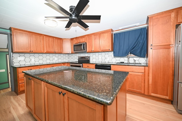 kitchen with a kitchen island, appliances with stainless steel finishes, sink, decorative backsplash, and light hardwood / wood-style floors