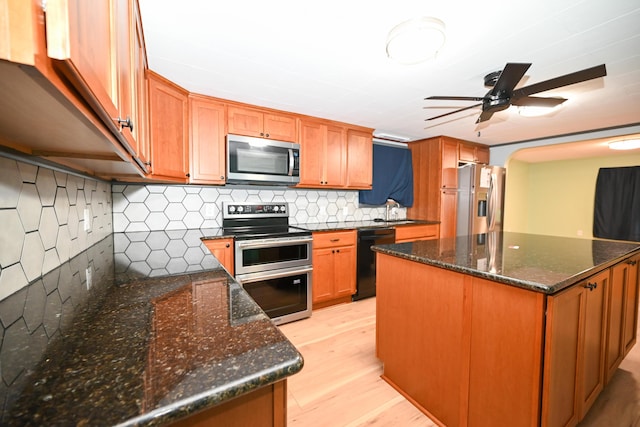 kitchen featuring tasteful backsplash, sink, dark stone counters, stainless steel appliances, and light hardwood / wood-style flooring